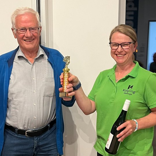 Steffi Kühl überreicht Alfons Schröer den „St. Josef Cup“ und eine Flasche Kolping-Wein.