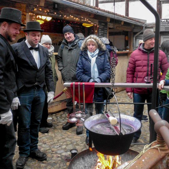 In der „Adventsstadt Quedlinburg“ bereiten die Gastgeber des Hofes „Pfeiffer mit drei f“ Feuerzangenbowle zu.